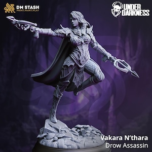 Puede incluir: Figura gris detallada de Vakara N'thara, una Asesina Drow, en una pose dinámica. Viste una armadura ornamentada y sostiene una ballesta y un arma con filo. La figura está sobre una base rocosa, con el logo "Under Darkness" visible.