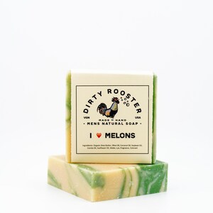 May include: A bar of natural soap with a green and white swirl pattern. The soap is labelled "Dirty Rooster" and "I ♥ Melons".