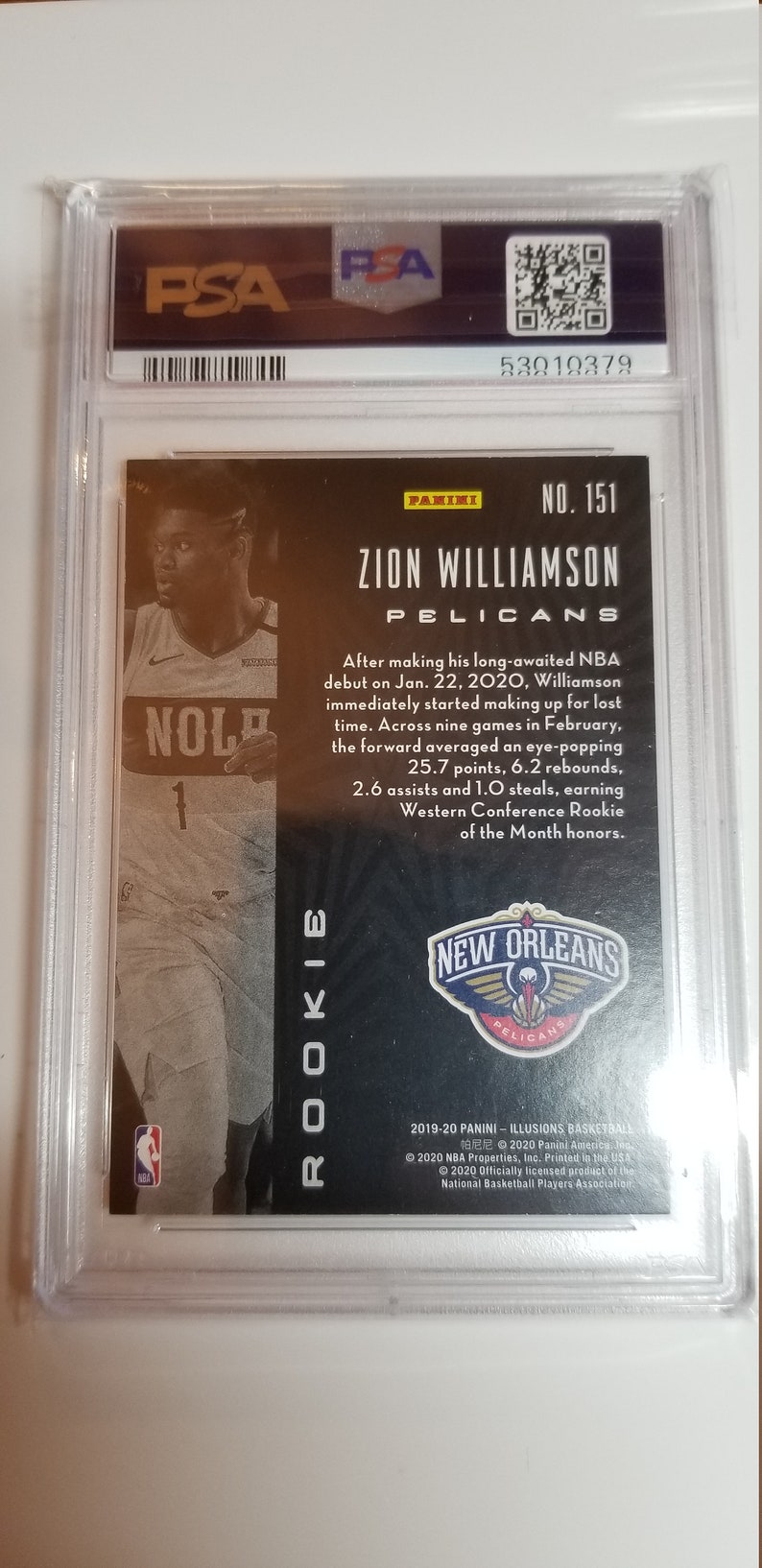 May include: A black and gold basketball trading card featuring Zion Williamson of the New Orleans Pelicans. The card is from the 2019-20 Panini Illusions Basketball set. The card number is 151.