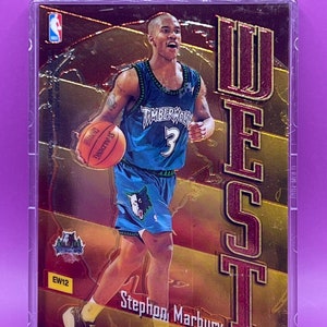 May include: A basketball trading card featuring Stephon Marbury in a blue and green Minnesota Timberwolves uniform. The card has a gold and red background with the word "WEST" in large red letters. The card number is EW12.