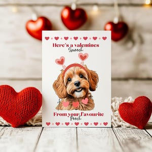 May include: Valentine's Day card with a smiling dog wearing a heart headband. The card says "Here's a valentines Smooch" and "From your favourite Pooch" with heart decorations. Red heart ornaments and knitted hearts are in the background.