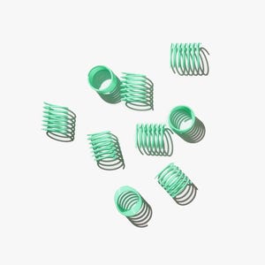May include: A collection of nine green metal hair curlers scattered on a white background. The curlers are in various positions and have a spring-like design.