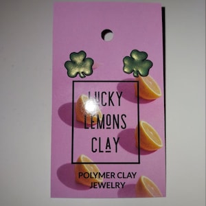 May include: A pair of green shamrock earrings on a pink background with the text "Lucky Lemons Clay" and "Polymer Clay Jewelry".