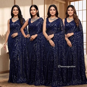 Puede incluir: Cuatro mujeres con saris azul marino con lentejuelas, con tops sin mangas y chales a juego. Cada mujer lleva un collar y una pulsera de plata. Los saris tienen un efecto brillante, sobre un fondo neutro. El texto "Dreamexporters" es visible.