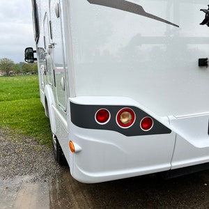 Puede incluir: Autocaravana blanca con un borde gris alrededor de las luces traseras. Las luces traseras tienen tres luces rojas y una luz &aacute;mbar.