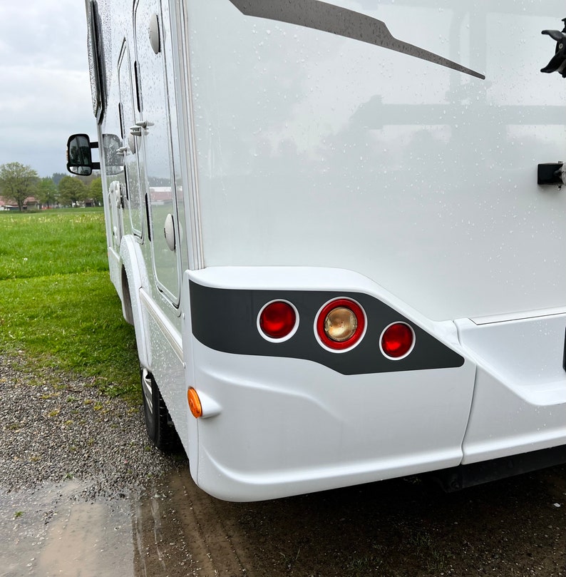 Puede incluir: Autocaravana blanca con un borde gris alrededor de las luces traseras. Las luces traseras tienen tres luces rojas y una luz &aacute;mbar.