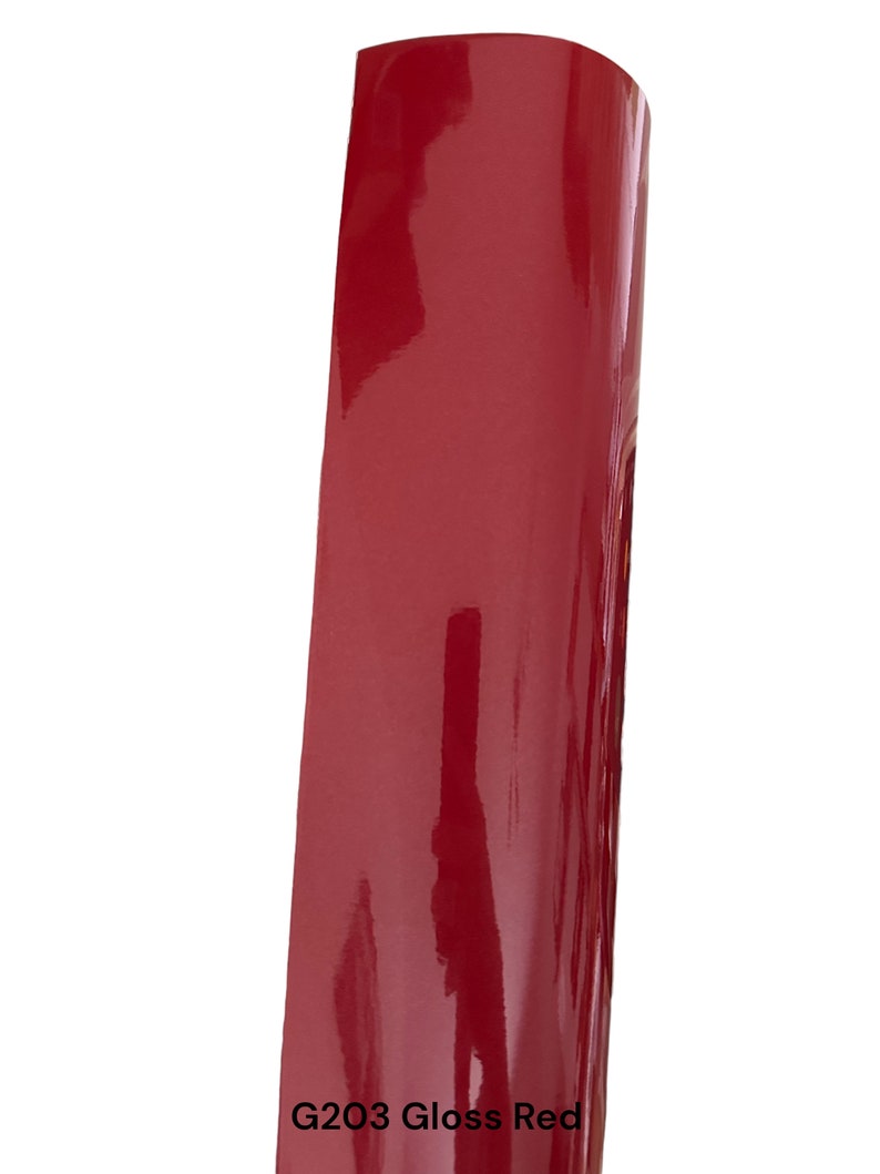 Puede incluir: Un primer plano de una muestra de vinilo rojo brillante. El vinilo es liso y brillante con un color rojo intenso. El texto "G203 Gloss Red" est&aacute; impreso debajo de la muestra.