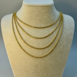May include: Five gold rope chains of varying lengths displayed on a cream-colored mannequin bust.