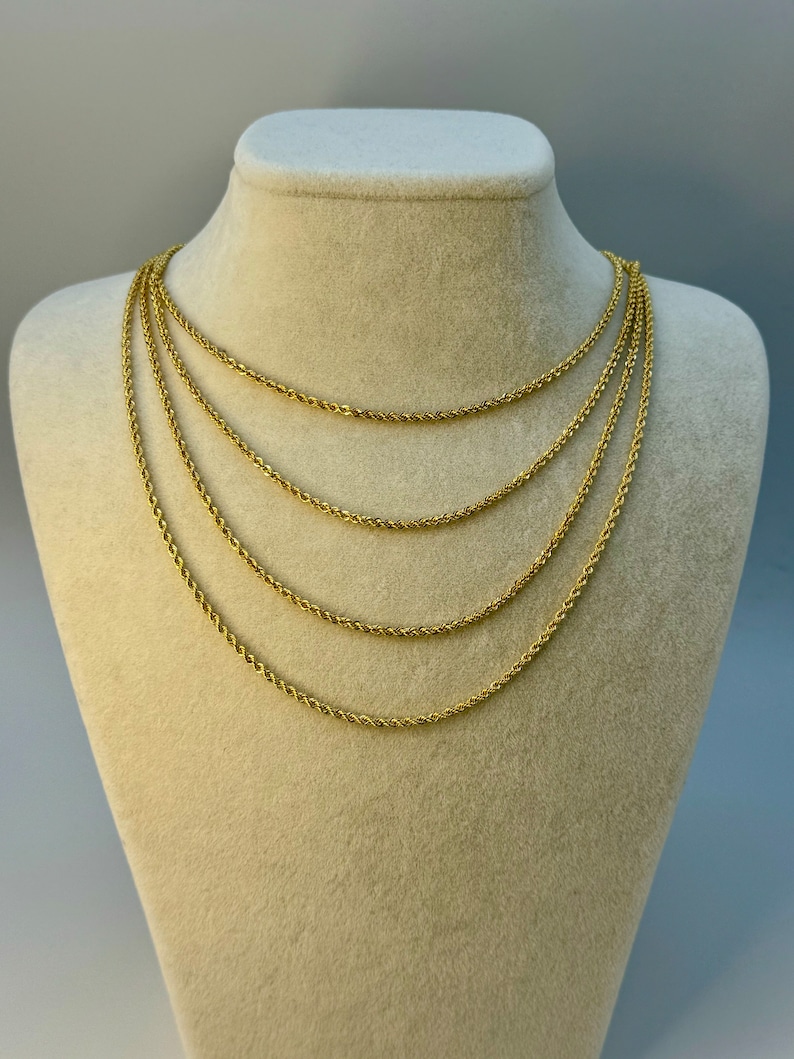 May include: Five gold rope chains of varying lengths displayed on a cream-colored mannequin bust.