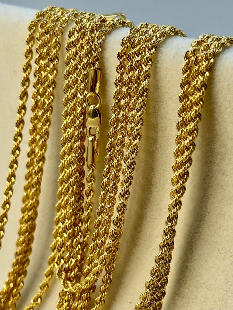 May include: A close-up of a gold rope chain necklace. The chain is made of multiple strands of twisted gold wire.
