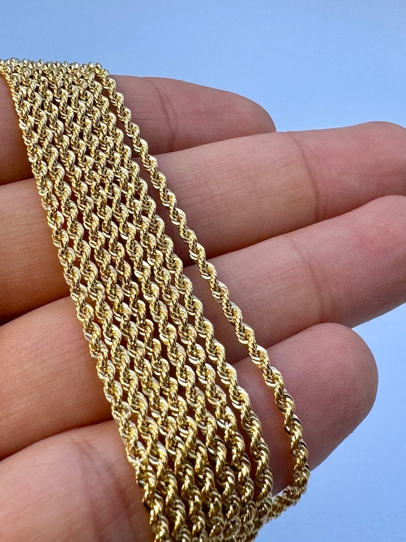 May include: A close-up of a gold rope chain necklace. The chain is made of multiple strands of twisted gold wire.