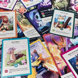 Könnte beinhalten: Eine Sammlung bunter Spielkarten mit Illustrationen verschiedener Tiere und Charaktere. Die Karten haben unterschiedliche Namen und Fähigkeiten, wie z. B. "Doe Fallow", "Raider" und "Heart of the Dead".