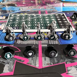 May include: A board game with six miniature figures on black bases with different symbols. The figures are gray and represent different characters. The game board is blue and gray with a pink border. The game board has a grid pattern and various symbols.