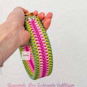 May include: A colorful dog collar in a woven pattern. The collar features a combination of green, pink, and yellow threads. The text "Guacamole Lime Zuckerwatte Bubblegum" is written in pink script.
