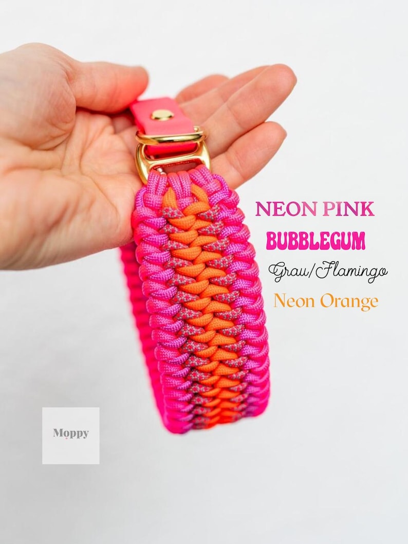 May include: A neon pink and orange dog collar with a gold-colored buckle. The collar is made of woven material and features the text "Neon Pink, Bubblegum, Grau/Flamingo, Neon Orange". The brand name "Moppy" is also visible.