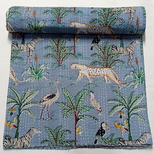 Könnte beinhalten: Eine aufgerollte, hellblaue Steppdecke mit einem Dschungelmotiv. Das Design zeigt Zebras, Leoparden, Vögel und üppiges grünes Laub. Die Steppdecke ist mit weißem Faden handgenäht und hat eine strukturierte Optik.