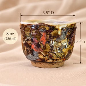 Puede incluir: Una taza de cerámica con un esmalte texturizado multicolor en tonos marrón, negro, naranja y crema. La taza mide 8,89 cm de diámetro, 6,35 cm de altura y tiene una capacidad de 236 ml. Presenta un borde ancho y una base estrecha.