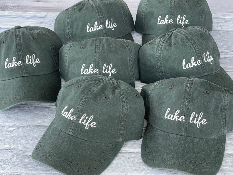K&ouml;nnte beinhalten: Sechs dunkelgr&uuml;ne Baseballkappen mit wei&szlig; gesticktem Text, der "lake life" lautet.