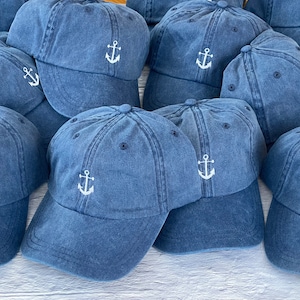 May include: A group of blue denim baseball caps with white embroidered anchors. The caps have a classic style and are perfect for casual wear.