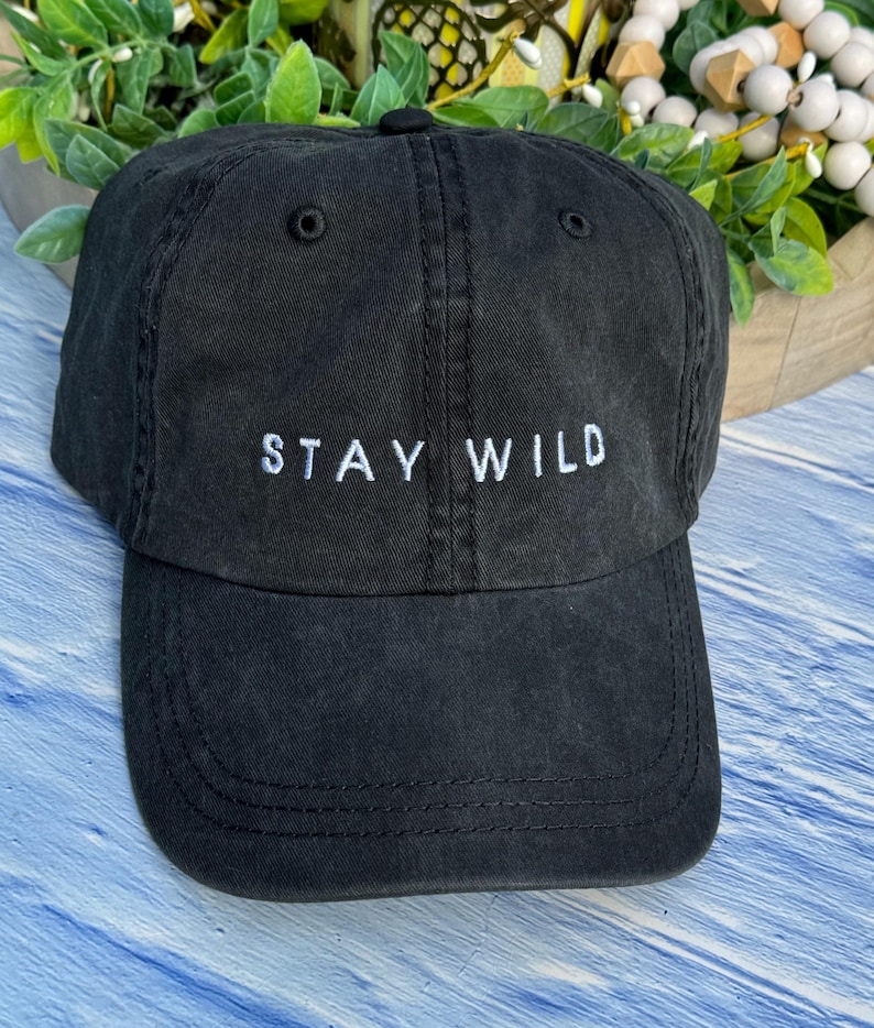 以下が含まれることがあります： 前面に「STAY WILD」という白い刺繍が施された黒い野球帽
