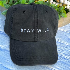 以下が含まれることがあります： 前面に「STAY WILD」という白い刺繍が施された黒い野球帽