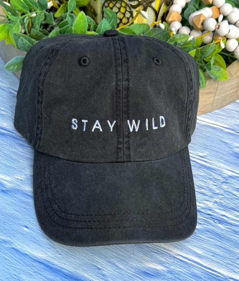以下が含まれることがあります： 前面に「STAY WILD」という白い刺繍が施された黒い野球帽