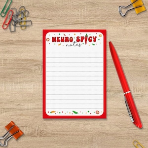 May include: Red notepad with the text "Neuro Spicy notes" in white letters. The notepad has a red border and a white background with a dotted line pattern. The notepad is decorated with red, green, and yellow chilli peppers.