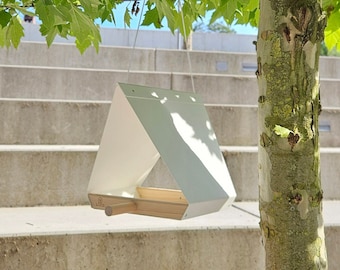 May include: A white bird feeder with a wooden base and a clear plastic roof. The feeder is hanging from a tree branch.