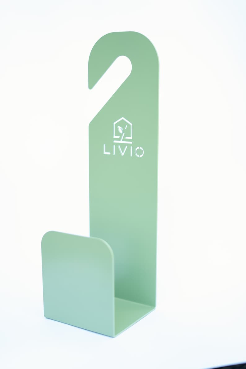 May include: A mint green metal hook with a curved base and a top hook for hanging. The word "LIVIO" is printed in white, along with a house and leaf logo. The hook is designed for organizing items.