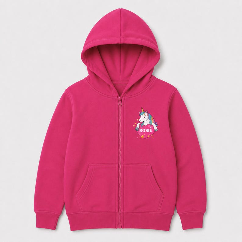 May include: A bright fuchsia zip-up hoodie featuring a hood, long sleeves, and two front pockets. On the left chest, there is a graphic of a white unicorn with a colorful mane resting on a pink heart that contains the name ROSIE in white text.