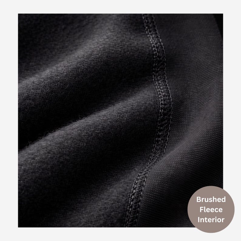 May include: A black fabric garment featuring a soft brushed fleece interior texture. The material displays a visible vertical seam with reinforced stitching connecting the fuzzy fleece side to a smoother, ribbed-knit fabric section on the right.