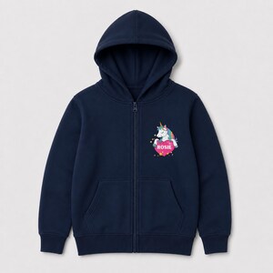 May include: A navy blue zip-up hoodie featuring a graphic on the left chest. The graphic depicts a white unicorn with a rainbow mane and a gold horn, resting on a pink heart that contains the name ROSIE in white capital letters.