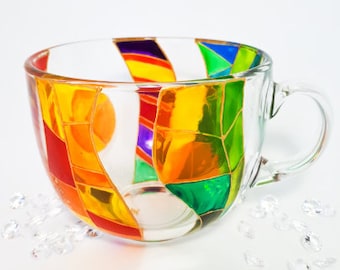 Pode incluir: Uma caneca de vidro com um design de vitral colorido. O design apresenta uma variedade de cores, incluindo vermelho, laranja, amarelo, verde, azul e roxo. A caneca é perfeita para adicionar um toque de fantasia ao seu café ou chá da manhã.