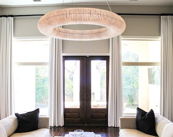 May include: A living room with two white sofas, a large round crystal chandelier, and white curtains flanking a set of double French doors.