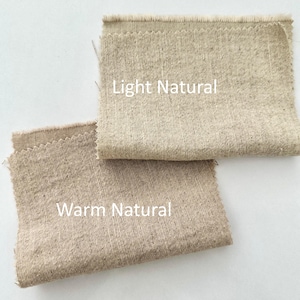 Pu&ograve; includere: Due campioni di tessuto rettangolari con bordi sfilacciati. Il campione superiore &egrave; etichettato Light Natural e presenta una trama testurizzata beige chiaro. Il campione inferiore &egrave; etichettato Warm Natural e mostra un tessuto color marrone.