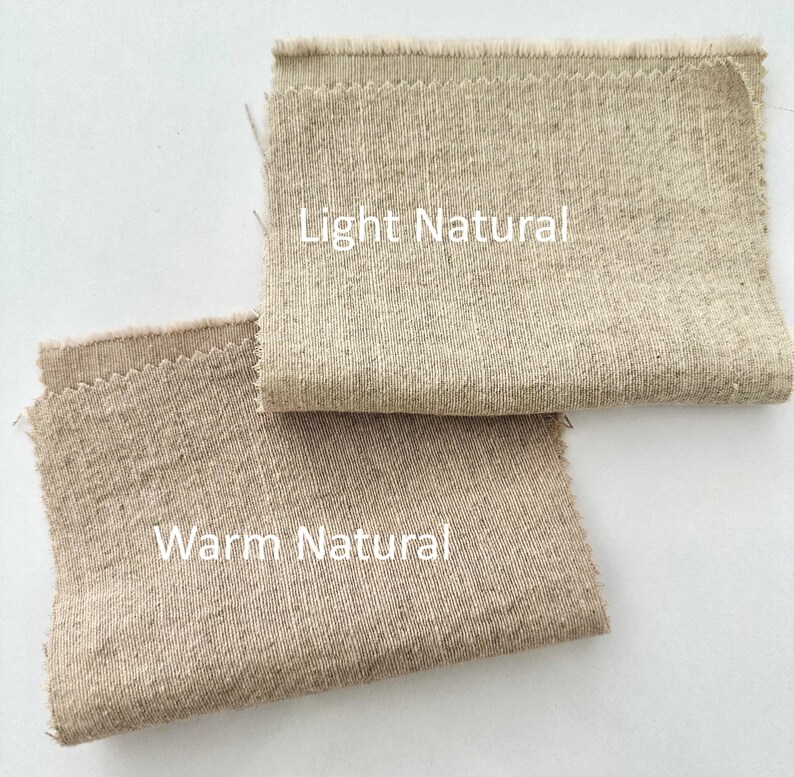 Pu&ograve; includere: Due campioni di tessuto rettangolari con bordi sfilacciati. Il campione superiore &egrave; etichettato Light Natural e presenta una trama testurizzata beige chiaro. Il campione inferiore &egrave; etichettato Warm Natural e mostra un tessuto color marrone.
