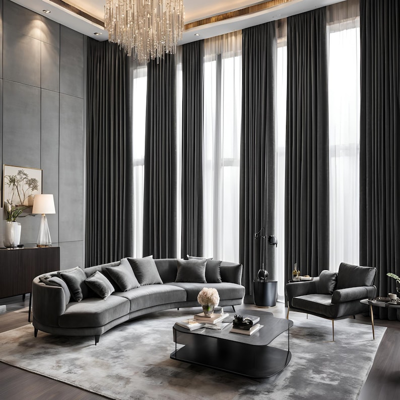 May include: A curved grey velvet sofa with multiple cushions sits in a modern living room with large windows and grey curtains. A black coffee table with a glass top sits in front of the sofa. A grey armchair with gold legs sits to the right of the sofa.