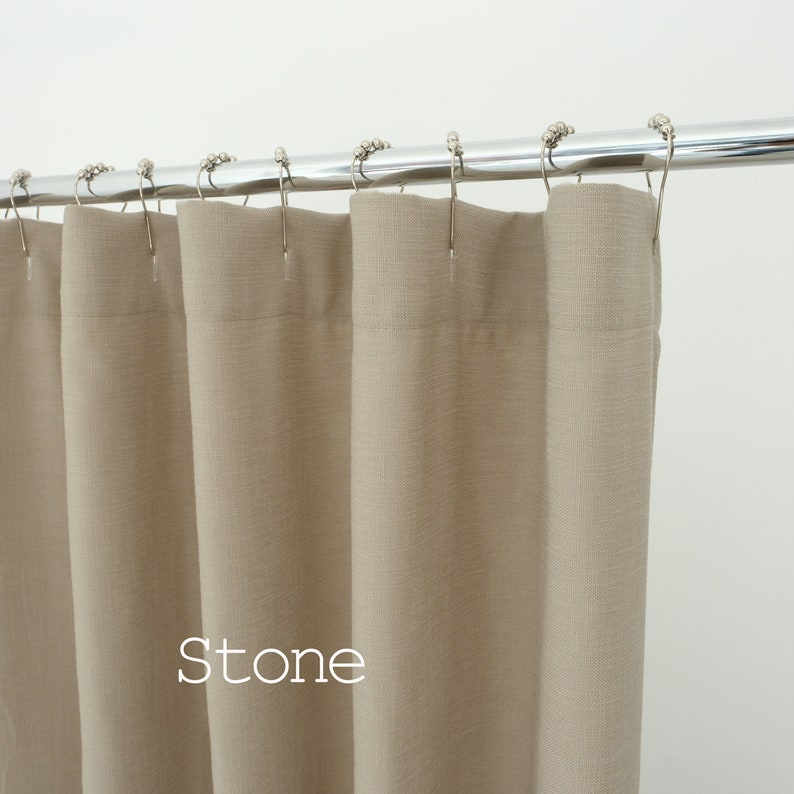 Pu&ograve; includere: Una tenda da doccia color pietra con una visibile trama in tessuto, appesa a un'asta in cromo lucido. La tenda &egrave; fissata all'asta tramite anelli in metallo argentato. La parola "Stone" &egrave; stampata in bianco sul tessuto della tenda.