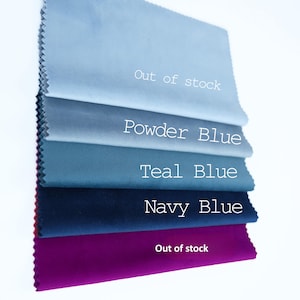 May include: A stack of five rectangular fabric swatches with pinked edges, featuring colors labeled as Out of stock, Powder Blue, Teal Blue, Navy Blue, and Out of stock. The fabric has a smooth, matte finish and is arranged in a vertical column.