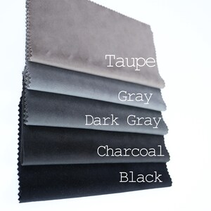 May include: A stack of five rectangular fabric swatches with pinked edges, arranged in a gradient from light to dark. The colors are labeled with white text as Taupe, Gray, Dark Gray, Charcoal, and Black, showcasing a smooth, matte texture.