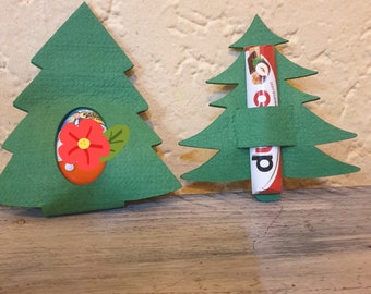 May include: Two green felt Christmas tree decorations. One tree has a red flower and a chocolate sweet inside. The other tree has a chocolate bar inside.
