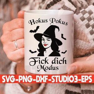 May include: White ceramic mug with the text "Hokus Pokus" and "Fick dich Modus" in black script. The mug features a winking witch illustration with a black hat and bats.