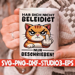 May include: White ceramic mug with a cartoon orange cat giving the middle finger. The text on the mug reads "Hab dich nicht beleidigt nur beschrieben!"