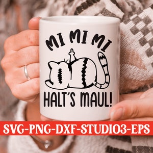 Peut inclure: Une tasse en céramique blanche avec une illustration noire et blanche d'un chat avec le texte "MI MI MI HALT'S MAUL!" imprimé dessus.