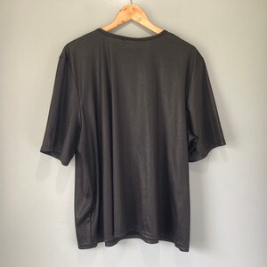 Puede incluir: Una camiseta negra de manga corta con cuello redondo.