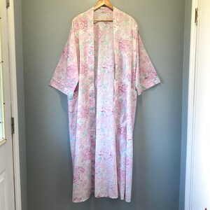 May include: A long white robe with a pink and blue floral pattern. The robe has a shawl collar and long sleeves.