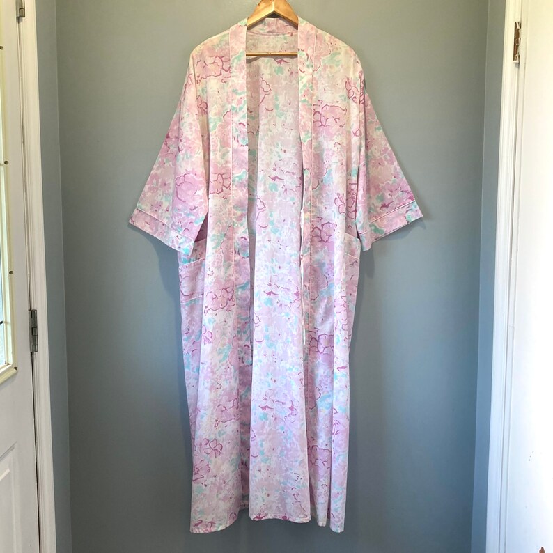 May include: A long white robe with a pink and blue floral pattern. The robe has a shawl collar and long sleeves.