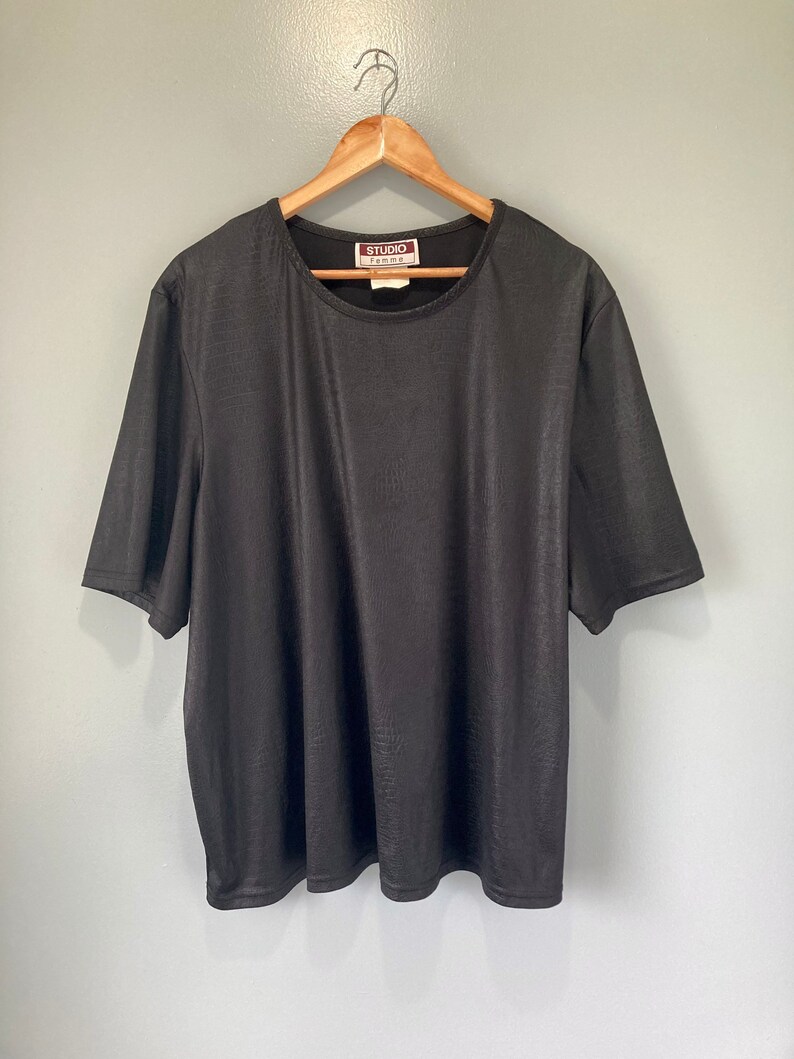 Puede incluir: Una camiseta negra de manga corta con cuello redondo. La camiseta tiene una etiqueta de STUDIO FEMME.