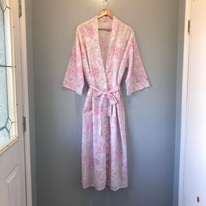 May include: A pink and white floral print dressing gown with a tie belt.