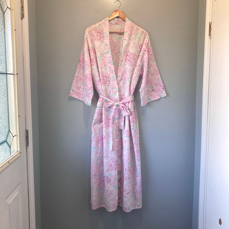 May include: A pink and white floral print dressing gown with a tie belt.